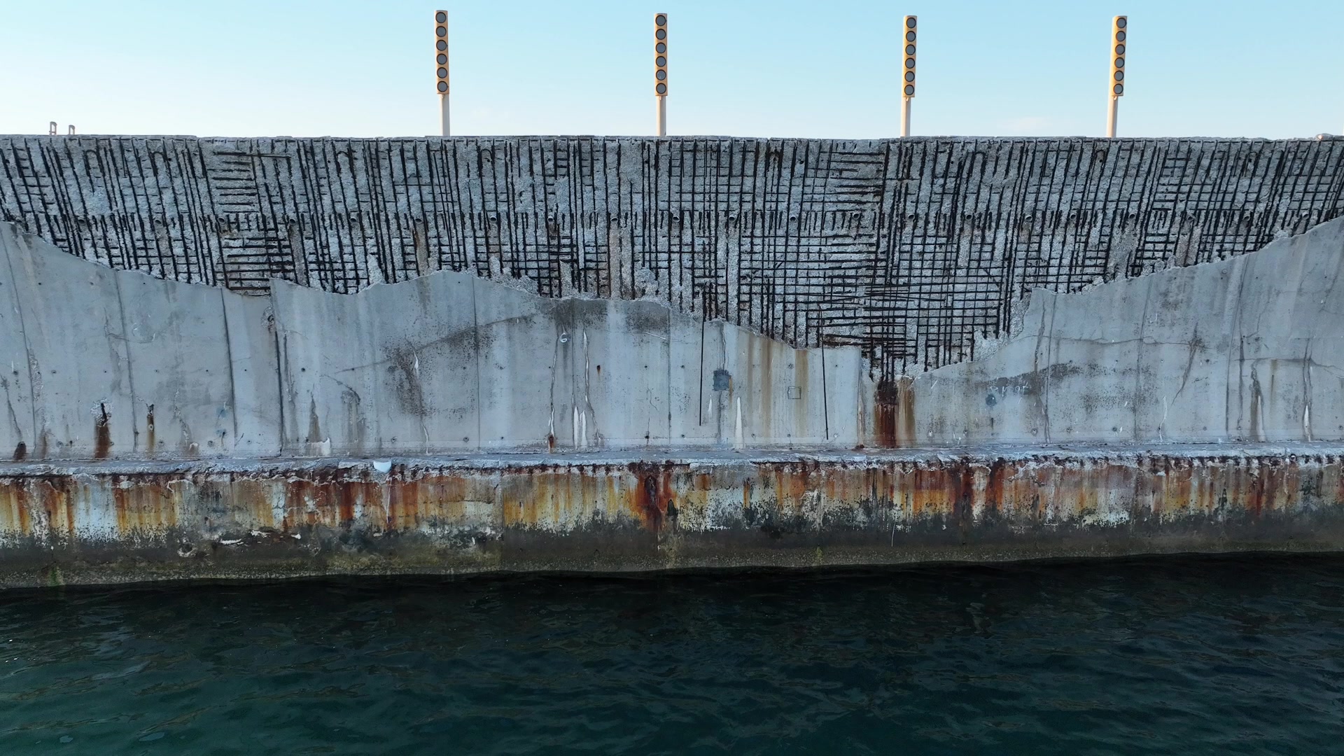 Detalle de la superficie de un muelle de Málaga, con manchas de oxidación junto al agua, capturado desde un dron